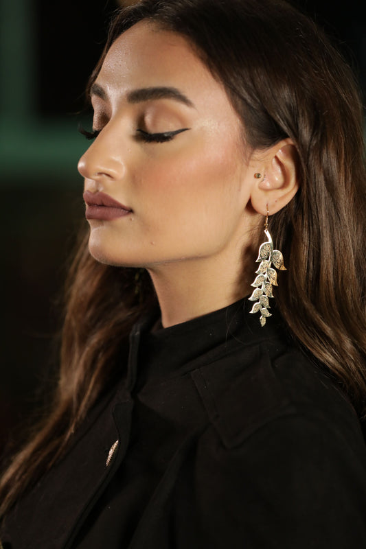 Woman wearing a black outfit with a gold earring against a dark background arabic