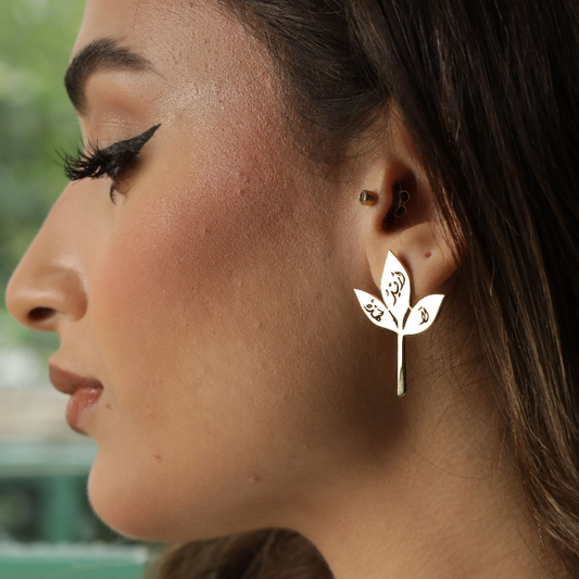 Close-up of a woman wearing a silver leaf-shaped earring with a blurred background