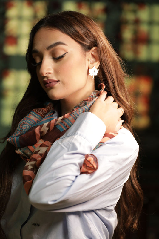 Woman wearing a patterned scarf and earrings with a blurred background