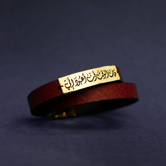 Burgundy leather bracelet with a gold rectangular tag on a dark blue background