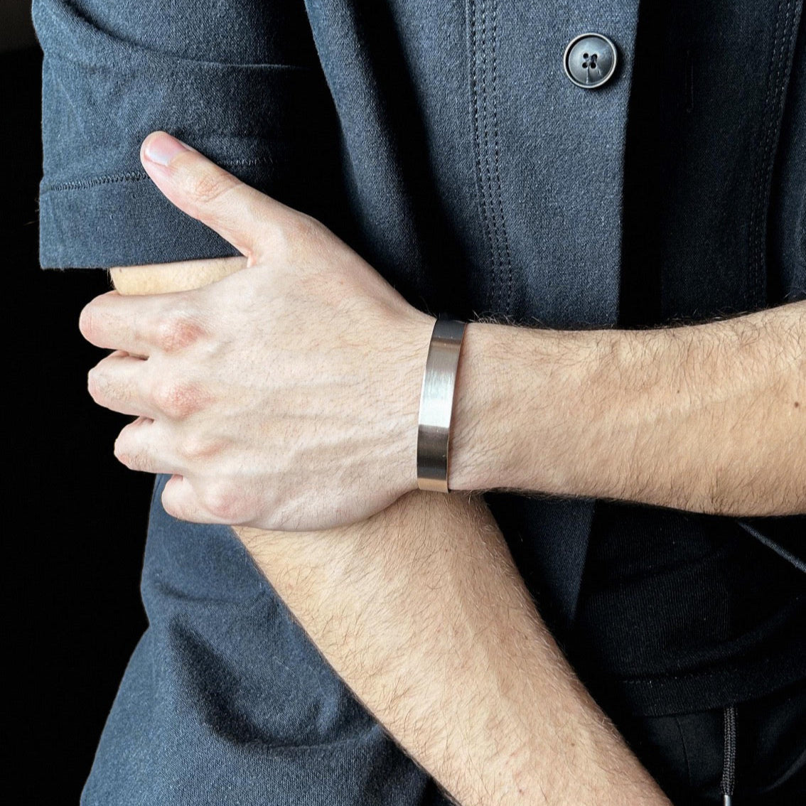 Person wearing a silver bracelet with a dark background